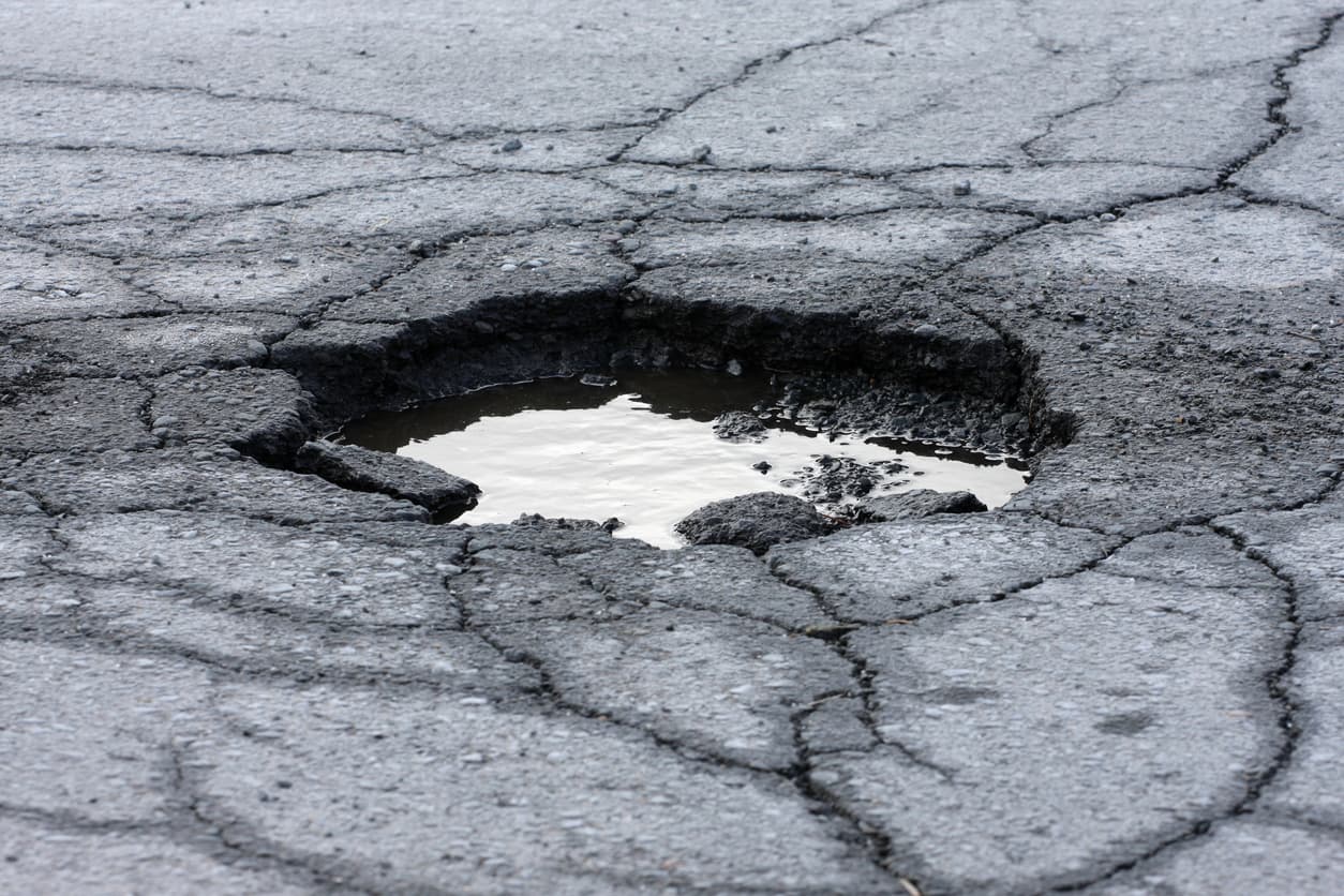 pothole-filled-with-water-and-surrounded-by-cracks-in-asphalt